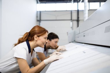 Laundry workers preparing towels for ironing. clipart