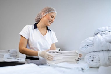 Kadın kuru temizlemeci temiz çamaşırları katlıyor ve doğum için hazırlanıyor..