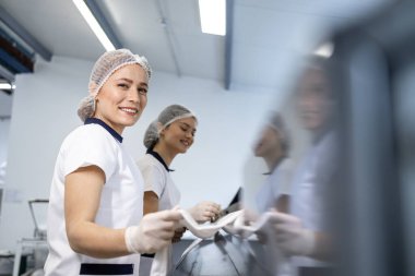 Female laundry workers preparing linen and bedsheets for ironing in dry cleaning service. clipart