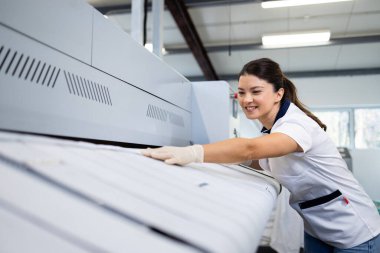 Endüstriyel ütü makinesi için çarşaf ve çarşaf hazırlayan güzel bir çamaşırcı..