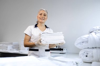 Kadın kuru temizlemeci temiz çamaşırları katlıyor ve doğum için hazırlanıyor..