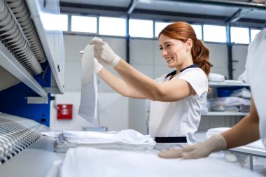 Çamaşır yıkayan kadınlar kuru temizleme servisinde ütü yaptıktan sonra çarşaf ve çarşaf katlıyorlar..