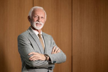 Ofisinde duran gülümseyen yakışıklı kıdemli işadamının portresi..