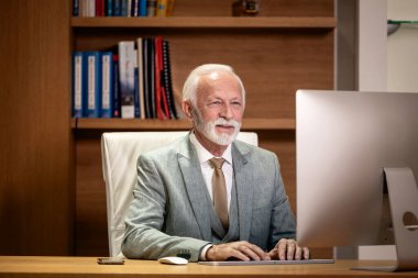 Şirket genel müdürü ofisinde çok çalışıyor. Masaüstü bilgisayarı kullanılıyor.