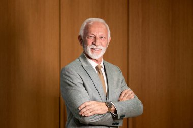 Ofisinde duran gülümseyen yakışıklı kıdemli işadamının portresi..