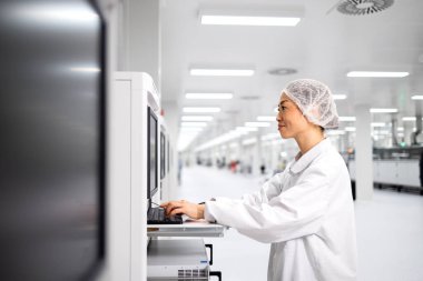 Japon fabrika işletmecisi endüstriyel makine üzerinde çalışıyor ve otomobil endüstrisindeki elektronik ekipman üretim sürecini kontrol ediyor.