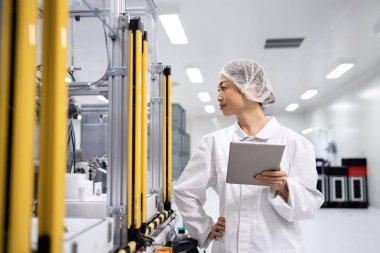 Japon mühendis bilgisayar çipleri ve elektronik bileşenler üreten son derece gelişmiş endüstriyel makinenin yanında duruyor.