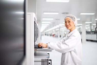 Japon fabrika işletmecisi endüstriyel makine üzerinde çalışıyor ve otomobil endüstrisindeki elektronik ekipman üretim sürecini kontrol ediyor.