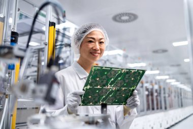 İleri teknoloji fabrikasında çalışan ve elektronik endüstrisi için basılı devre kartının kalitesini kontrol eden Japon mühendis..