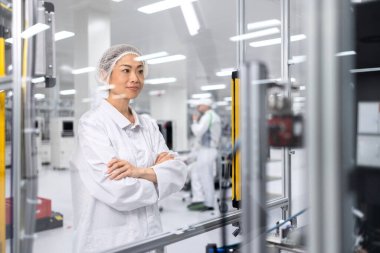 Otomobil endüstrisindeki elektronik ekipman üretim sürecini kontrol eden Japon fabrika işçisi.