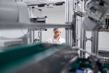 İleri teknoloji fabrikasında çalışan Japon mühendis. Elektronik endüstrisinde bilgisayar çipi üretimi. Arka planda robotik kol makineleri.