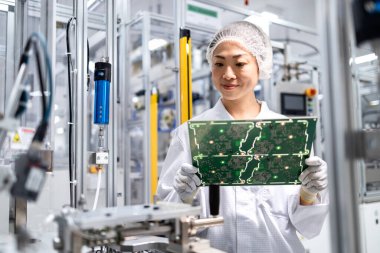 İleri teknoloji fabrikasında çalışan ve elektronik endüstrisi için basılı devre kartının kalitesini kontrol eden Japon mühendis..