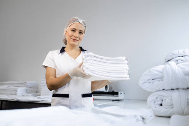 Kadın kuru temizlemeci temiz çamaşırları katlıyor ve doğum için hazırlanıyor..