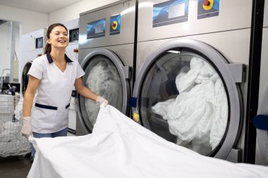 Güzel kadın çamaşırcı kuru temizleme servisinde temiz çarşaf katlıyor..