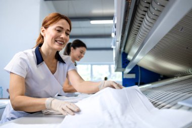 Mutlu, güzel kadın işçiler kuru temizlemecideki temiz çamaşırları katlıyor..
