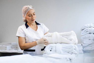 Kadın çamaşırcı, temiz havlu katlıyor ve müşteriler için hazırlanıyor..