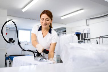 Kuru temizleme servisinde çamaşırları ütüleyen kadın çamaşırcı..