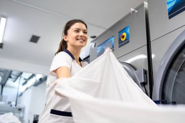 Güzel kadın çamaşırcı kuru temizleme servisinde temiz çarşaf katlıyor..