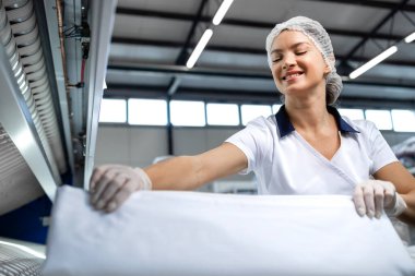 Gülümseyen kadın işçilerin portresi temiz çamaşırları kuru temizleme servisinde katlıyor..