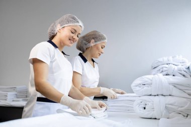 Kadın çamaşırcılar temiz havlu katlıyor ve müşteriler için hazırlanıyor..