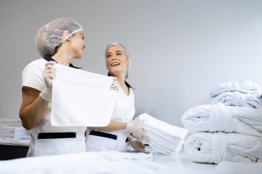 Kadın çamaşırcılar temiz havlu katlıyor ve müşteriler için hazırlanıyor..