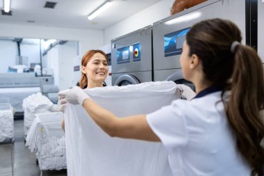 Kadın işçiler kuru temizleme servisinde birlikte temiz çamaşır katlamayı severler..