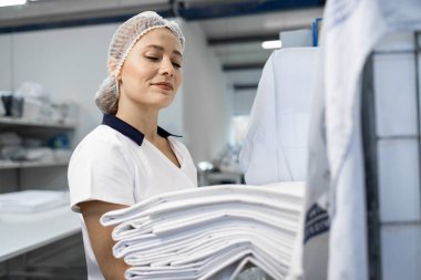 Profesyonel kuru temizlemeci. Müşteri için katlanmış temiz çamaşırları paketliyor..