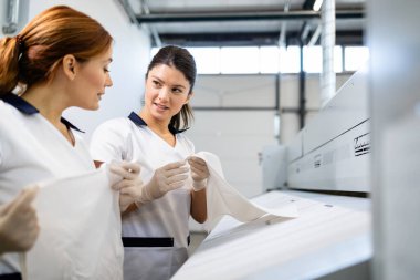 Otel servisi için çarşaf ve çarşaf ütüleyen profesyonel çamaşır işçileri. Kuru temizlemecide çalışıyorum..