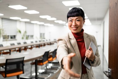 İş elbisesinde başarılı bir Japon yönetici konferans odasında insanları karşılıyor..