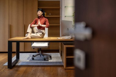 Huzurlu iş kadını meditasyon yapıyor ve iş tatilinde ofisinde yoga egzersizleri yapıyor..