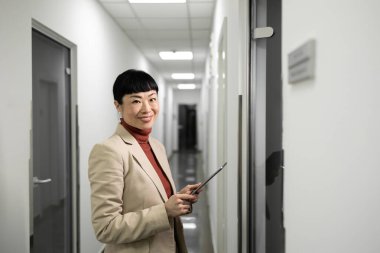 Ofisinin yanındaki şirket koridorunda duran başarılı Japon iş kadını müdürünün portresi. Şirket içi.