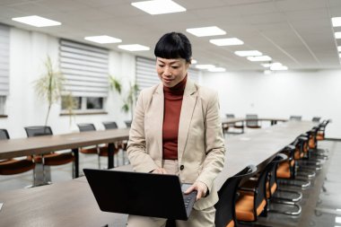 Ofiste dizüstü bilgisayar kullanan zeki Japon iş kadınının portresi..