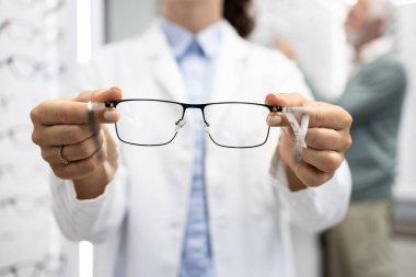 Optik mağazasında gözlükçünün tuttuğu gözlüklerin görüntüsünü kapat.