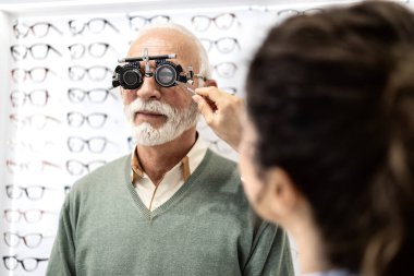 Profesyonel göz doktoru ya da göz doktoru göz kliniğinde kıdemli erkek görme ve diyopter testleri yapıyor..