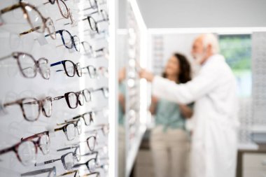 Optik mağazasında satılık gözlük ve gözlükçü müşterinin en iyi çerçeveyi seçmesine yardım ediyor.