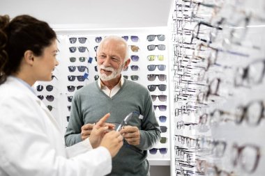 Kadın göz doktoru, gözlükçüdeki en iyi gözlük çerçevesini seçmesine yardımcı oluyor..