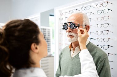 Kadın optometrist yaşlı adamın görüşünü ve görüşünü inceliyor. Katarakt göz hastalığı.