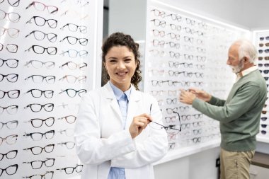 Gözlükçü dükkanında duran gülümseyen göz doktorunun portresi..