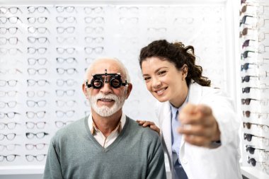 Tecrübeli bir optometrist, gözlük cihazı ve göz grafiği kullanarak üst düzey bir adamın görüş açısını, odaklanma ve diopterini kontrol ediyor..