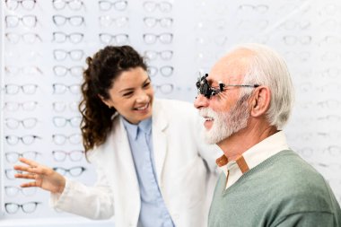 Tecrübeli bir optometrist, gözlük cihazı ve göz grafiği kullanarak üst düzey bir adamın görüş açısını, odaklanma ve diopterini kontrol ediyor..