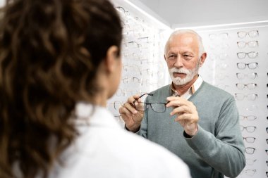Kıdemli adam yeni gözlük konusunda deneyimli bir gözlükçüye danışıyor..