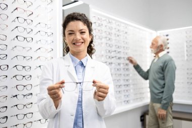 Gözlükçü dükkanında duran gülümseyen göz doktorunun portresi..