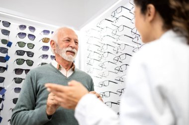 Kıdemli adam yeni gözlük almak isteyen deneyimli bir gözlükçüye danışıyor..