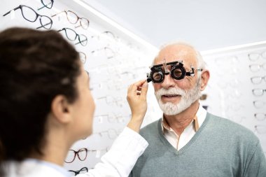Tecrübeli bir optometrist, gözlük cihazı ve göz grafiği kullanarak üst düzey bir adamın görüş açısını, odaklanma ve diopterini kontrol ediyor..