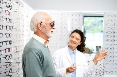 Tecrübeli bir optometrist, gözlük cihazı ve göz grafiği kullanarak üst düzey bir adamın görüş açısını, odaklanma ve diopterini kontrol ediyor..