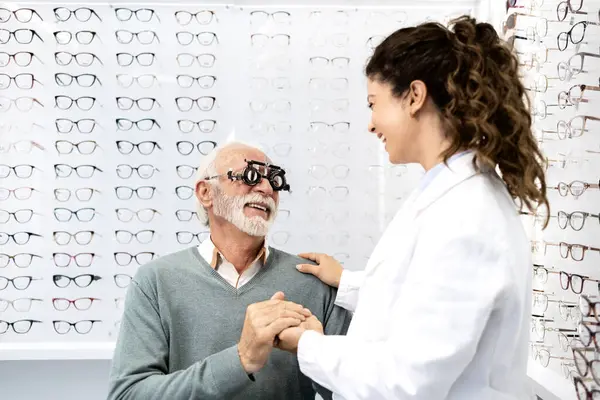 Optik mağazasında gülen ve el ele tutuşan oftalmolog ve hasta. Doktor ve hasta arasındaki ilişki.