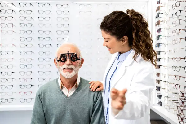 Tecrübeli bir optometrist, gözlük cihazı ve göz grafiği kullanarak üst düzey bir adamın görüş açısını, odaklanma ve diopterini kontrol ediyor..