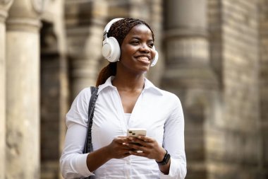 Şehir caddesinde yürürken telefon kullanan mutlu siyah kadın. Yaşam tarzı ve seyahat.