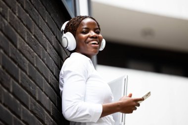 İş dünyası bölgesinde dizüstü bilgisayarlı gülümseyen iş kadını portresi.