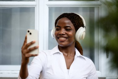 Müzik dinlerken kendi portresini çeken pozitif siyah bir kız..